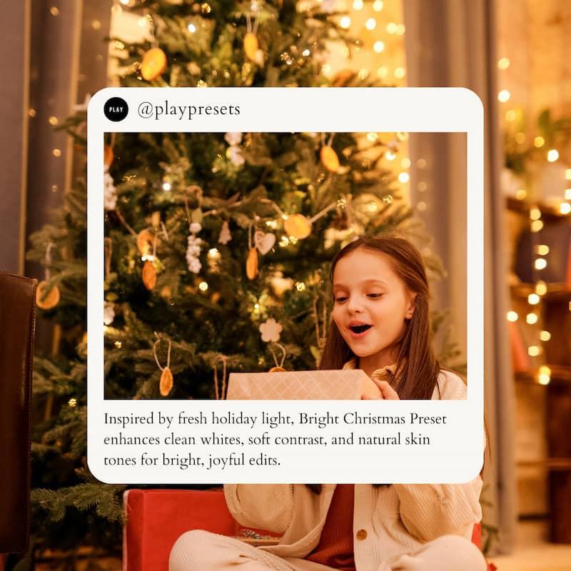 Young girl opening a present in front of a decorated Christmas tree with warm lighting enhanced with Christmas Family Lightroom presets