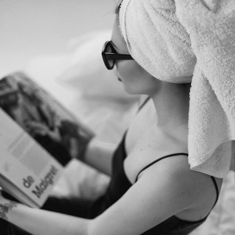 Person reading a book with a towel on their head edited with Ilford B&W Preset Collection.